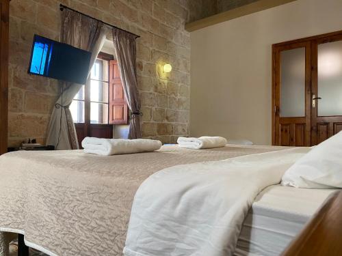two beds in a room with a tv on the wall at Xemx in Qala