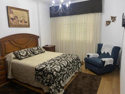 een slaapkamer met een bed en een blauwe stoel bij Piso O cruceiro in O Grove