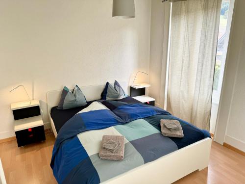 um quarto com uma cama azul e branca com almofadas em Appartement em Couvet