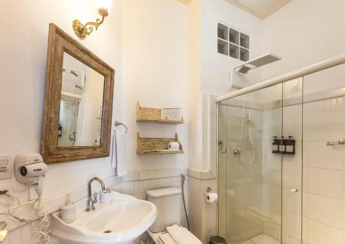 a white bathroom with a sink and a shower at Pousada Solar dos Deuses in Salvador