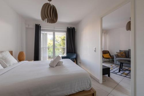 une chambre avec un grand lit blanc et un salon dans l'établissement Appartement T2 à l'Arbre Blanc, à Montpellier