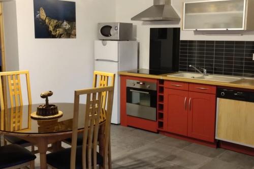 eine Küche mit roten Schränken, einem Tisch und einem Kühlschrank in der Unterkunft Gite de la longue fosse in Mandeville-en-Bessin