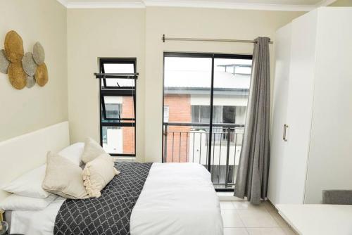 um quarto com uma cama e uma grande janela em Cozy Hidden gem in Midrand em Midrand