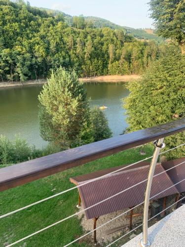 a bench on a balcony overlooking a lake at Casa Pescarului Apuseni in Sohodol