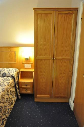 a bedroom with a bed and a large wooden cabinet at Olympic House Hotel in London
