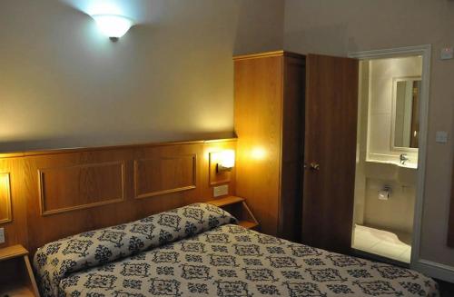 a small bedroom with a bed and a mirror at Olympic House Hotel in London