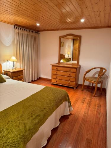 a bedroom with a bed and a mirror and a chair at O Cabaleiro in Santa Marta de Ortigueira