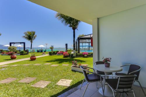 a patio with a table and chairs on the grass at Hotel Sete Ilhas in Florianópolis