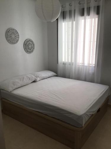 1 cama en un dormitorio con ventana y sábanas blancas en Residence Angelina, en San Miguel de Salinas