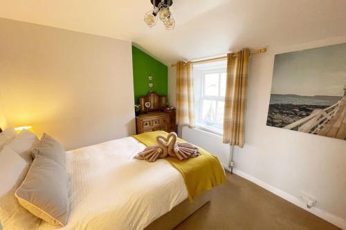 a bedroom with a large white bed with a window at A charming cottage set in Bridgetown Totnes. in Dean