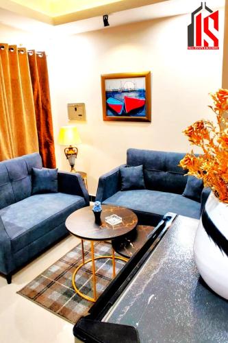 a living room with blue couches and a table at Sweet Retreat Loft in Rawalpindi
