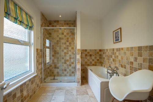 un bagno con vasca, doccia e lavandino di Large pretty holiday cottage by the sea sleeps 10 a Heacham