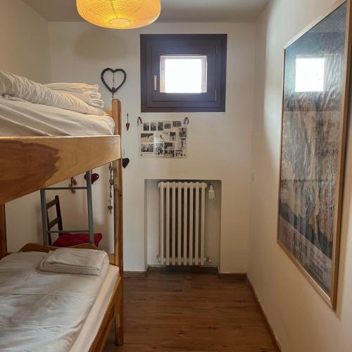 Cette chambre comprend 2 lits superposés, une fenêtre et un radiateur. dans l'établissement appartamento Cervinia fronte Funivie CIR 0480, à Breuil-Cervinia