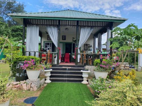 a home with a gazebo with plants and flowers at Agnes Cottage - Emerald in La Digue