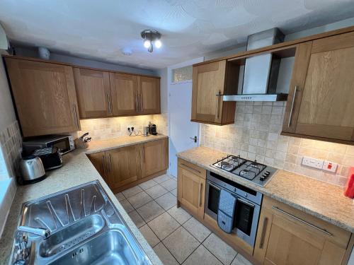 a kitchen with wooden cabinets and a stove top oven at Fabulous Bungalow Norwich in Norwich