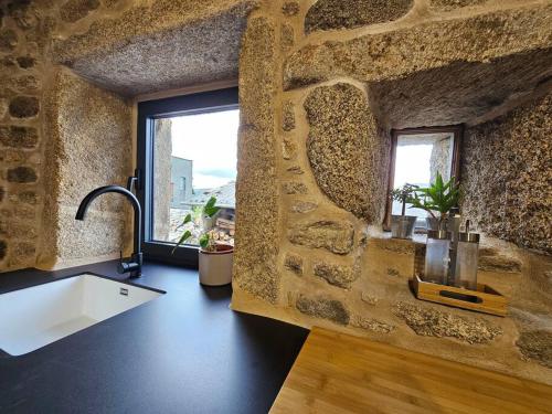 a stone kitchen with a sink and a window at Casa Gure Amets - Costa da Morte in A Coruña
