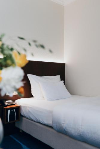 a bed with white sheets and pillows next to a table at Hotel Reindl Suiten & Appartments in Bad Füssing
