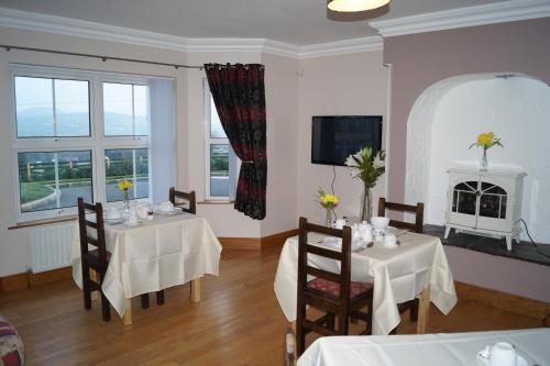 ein Esszimmer mit 2 Tischen und einem Kamin in der Unterkunft Clonmurr B&B in Ballyroney