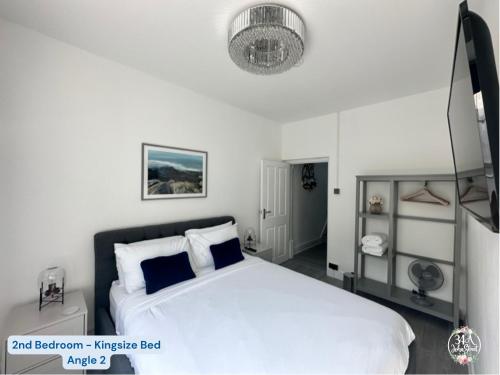 een slaapkamer met een groot wit bed en een kroonluchter bij OCEAN ESCAPE 200m From the Sea, High Spec Town Centre Entire Flat, 3 Bedrooms, TVs All Rooms in Porthcawl