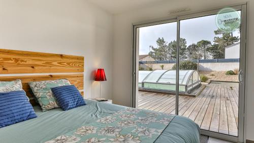 Schlafzimmer mit einem Bett und einer Glasschiebetür in der Unterkunft Villa Fleur de Dune in Saint-Jean-de-Monts