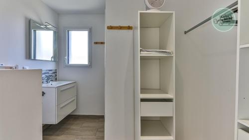 ein Badezimmer mit weißen Schränken und einem Waschbecken in der Unterkunft Villa Fleur de Dune in Saint-Jean-de-Monts