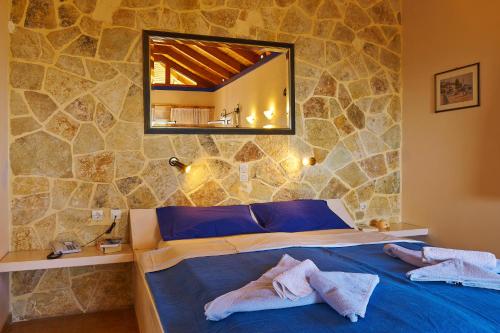 a bedroom with a blue bed and a mirror at Villas Cavo Marathia in Keri