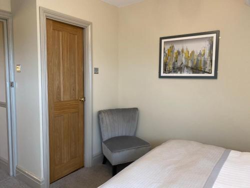 a bedroom with a bed and a chair next to a door at Ashbourne House in York