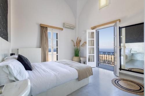 a bedroom with a bed and a view of the ocean at Bluewhite Villa Santorini in Pirgos
