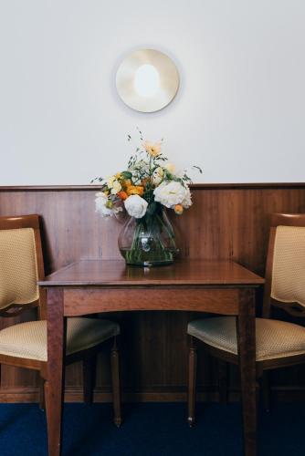 a vase of flowers on a wooden table with chairs at Hotel Reindl Suiten & Appartments in Bad Füssing