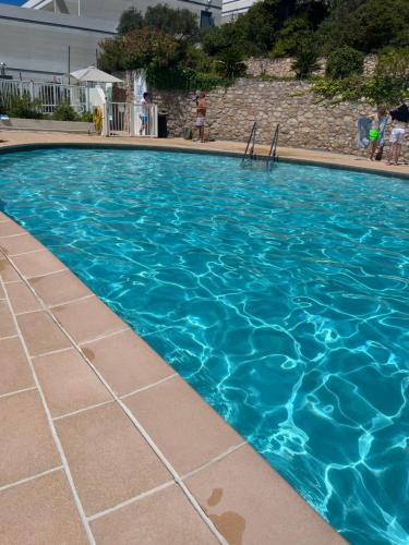 une grande piscine avec de l'eau bleue dans l'établissement VUE EPOUSTOUFLANTE SUR BANDOL & LA MER 2 pièces, piscine tout confort 4 étoiles, très calme, terrasse spacieuse sans vis à vis, parking privé résidence standing, à Bandol