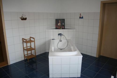 ein Badezimmer mit einer weißen Badewanne und einem Holzstuhl in der Unterkunft family & friends in Wernigerode