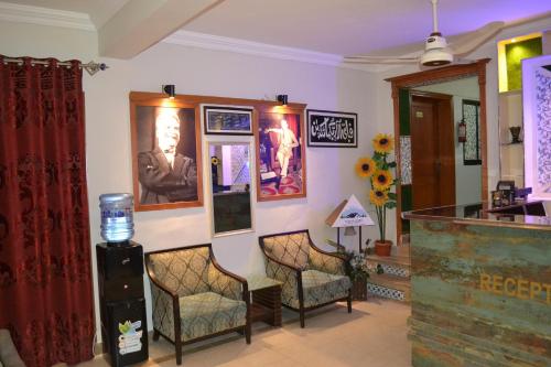 uma sala de espera com cadeiras e quadros na parede em Fusion Lodge em Islamabad