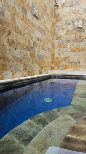 a swimming pool in a room with a stone wall at Fora Capsule Hostel Tuban Kuta Bali in Kuta