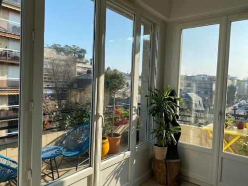 d'un balcon avec des fenêtres et des plantes en pot. dans l'établissement Superbe appartement lumineux, à Neuilly-sur-Seine