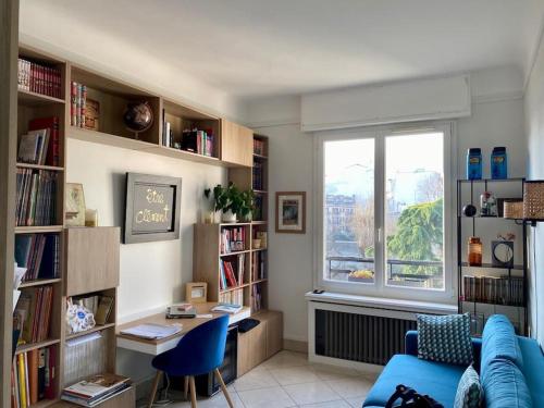 - un salon avec un canapé bleu, un bureau et une fenêtre dans l'établissement Superbe appartement lumineux, à Neuilly-sur-Seine