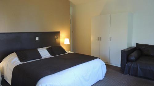 クレシーにあるHotel du Golf de Clécyのベッドルーム(白黒のベッド1台、椅子付)