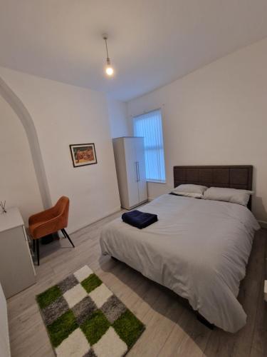 um quarto com uma cama grande e uma cadeira em Alton Rd guesthouse em Liverpool