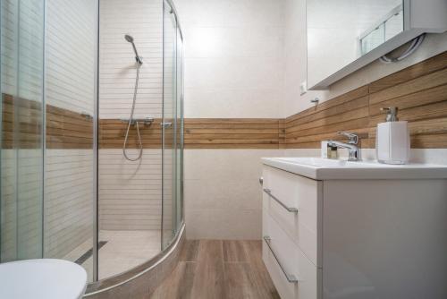 ein Badezimmer mit Dusche und Waschbecken in der Unterkunft La Vida apartman Hajdúszoboszló in Hajdúszoboszló