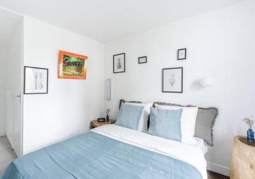 een witte slaapkamer met een bed met blauwe kussens bij Sauvage in Vincennes