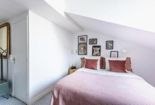 een witte slaapkamer met een groot bed met roze lakens bij Sauvage in Vincennes