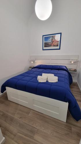 ein blaues Bett mit zwei Handtüchern darauf in einem Schlafzimmer in der Unterkunft Casa Helios in Capaci