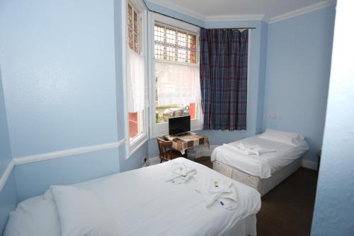 a blue room with two beds and a window at Charlie Hotel in London