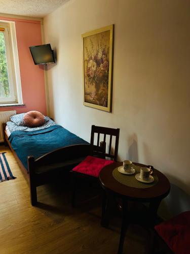 a room with a bed and a table with a chair at Domek w Lesie in Karłów