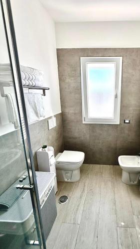 a bathroom with a toilet and a sink and a window at MaurusHome come a casa tua. in Fiumicino