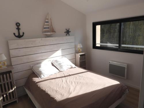 une chambre avec un lit avec des draps blancs et une fenêtre dans l'établissement Appartement à Andernos les bains proche plage, à Andernos-les-Bains
