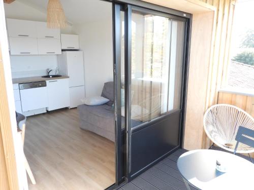- un salon avec une porte coulissante en verre menant à une cuisine dans l'établissement Appartement à Andernos les bains proche plage, à Andernos-les-Bains
