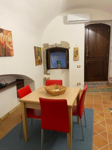 Casa Carini في شاكا: غرفة طعام مع طاولة خشبية وكراسي حمراء