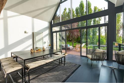 - une salle à manger avec une table, des chaises et de grandes fenêtres dans l'établissement Maison Oseraie, à Beynes