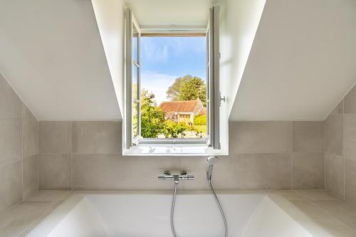 La salle de bains est pourvue d'une baignoire et d'une fenêtre. dans l'établissement Maison Oseraie, à Beynes