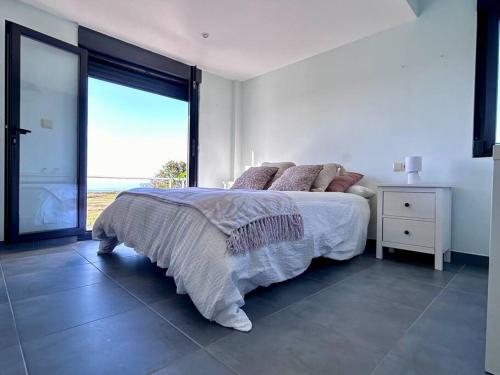 a white bedroom with a bed and a large window at Blanca Mañana in Ribeira